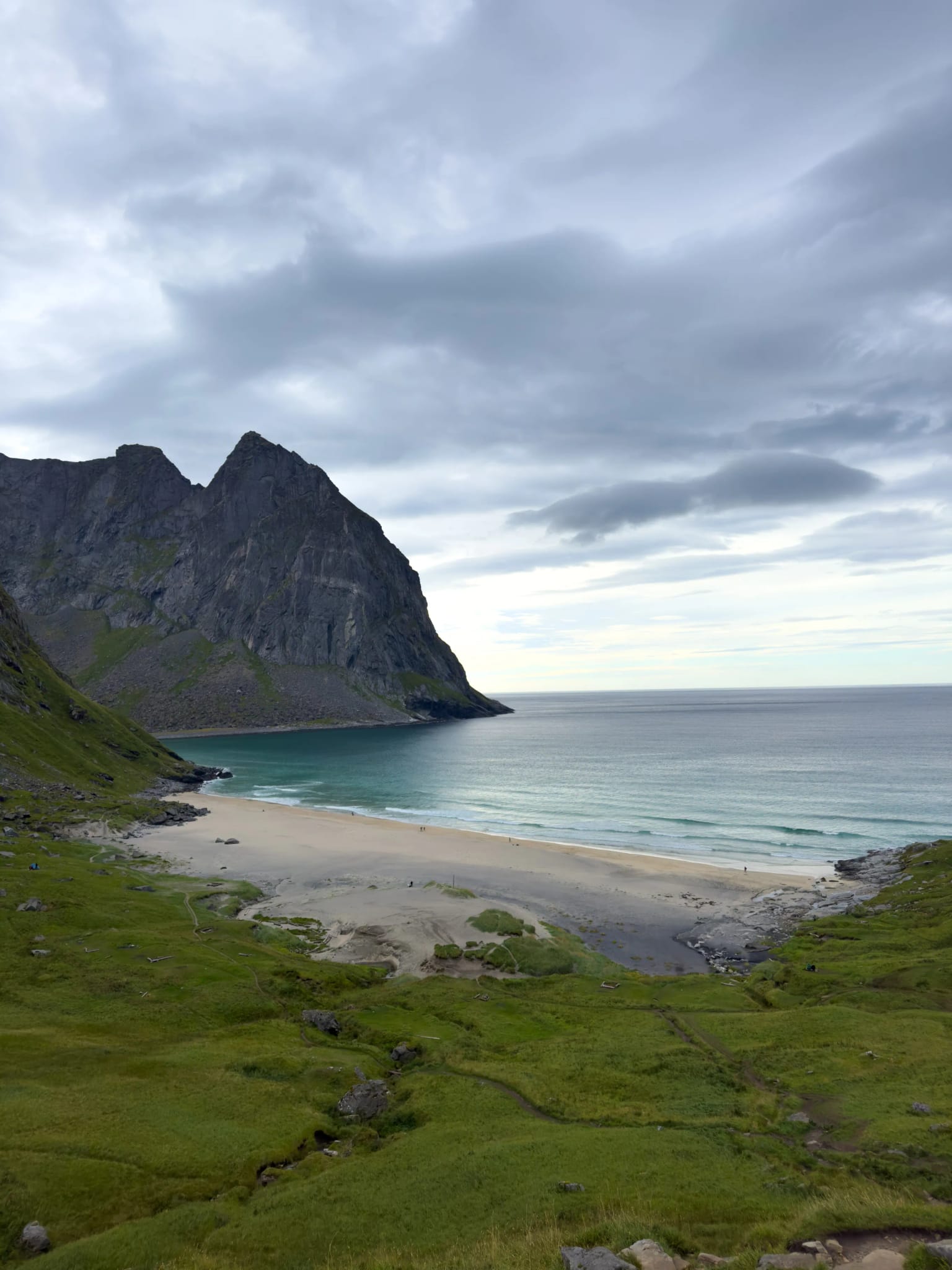 Dzika plaża Kvalvika z białym piaskiem i turkusową wodą otoczona klifami